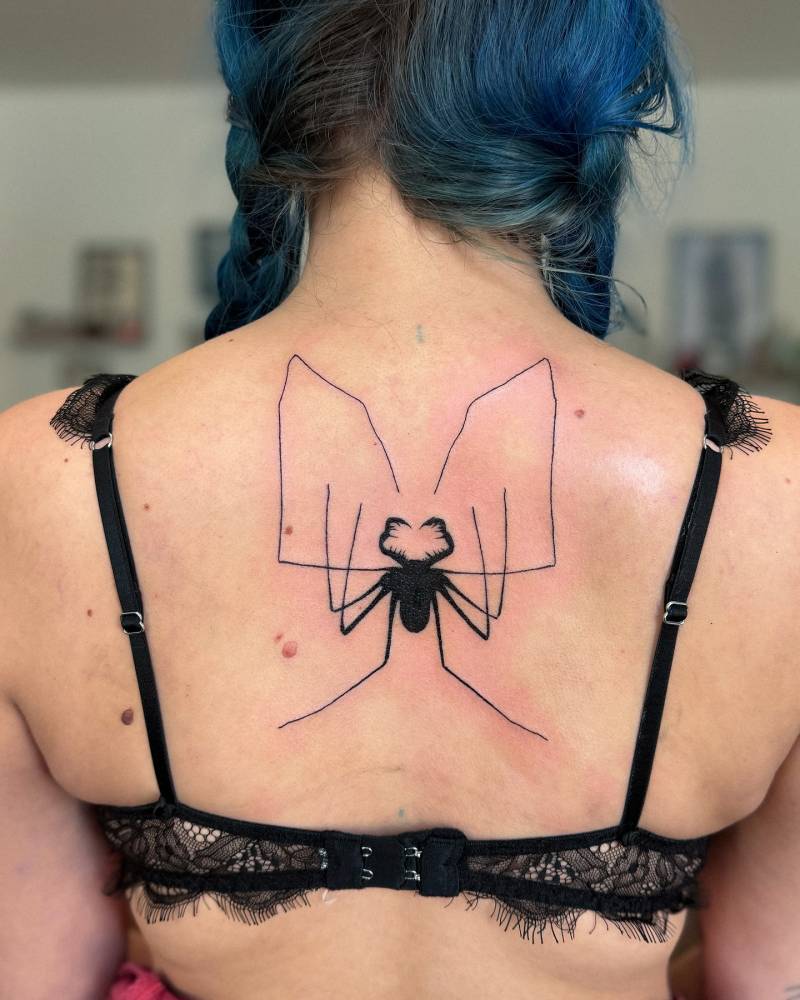 Blackwork style spider tattoo located on the upper back.