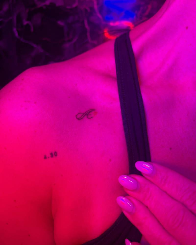 Scrip font letter "A" tatoo located on the collarbone.