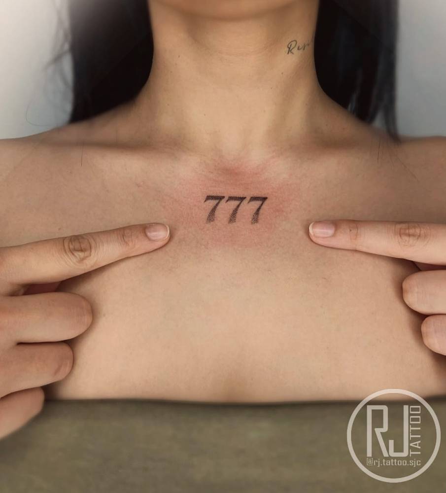 Serif font angel number "777" tattooed on the collarbone.