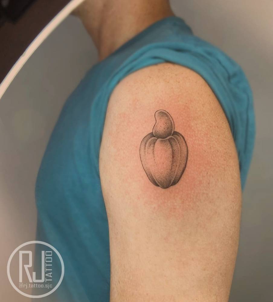 Cashew fruit tattooed on the upper arm, illustrative style.