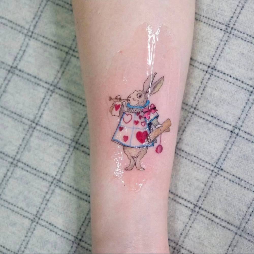 White Rabbit tattoo in cartoon style located on the inner forearm.