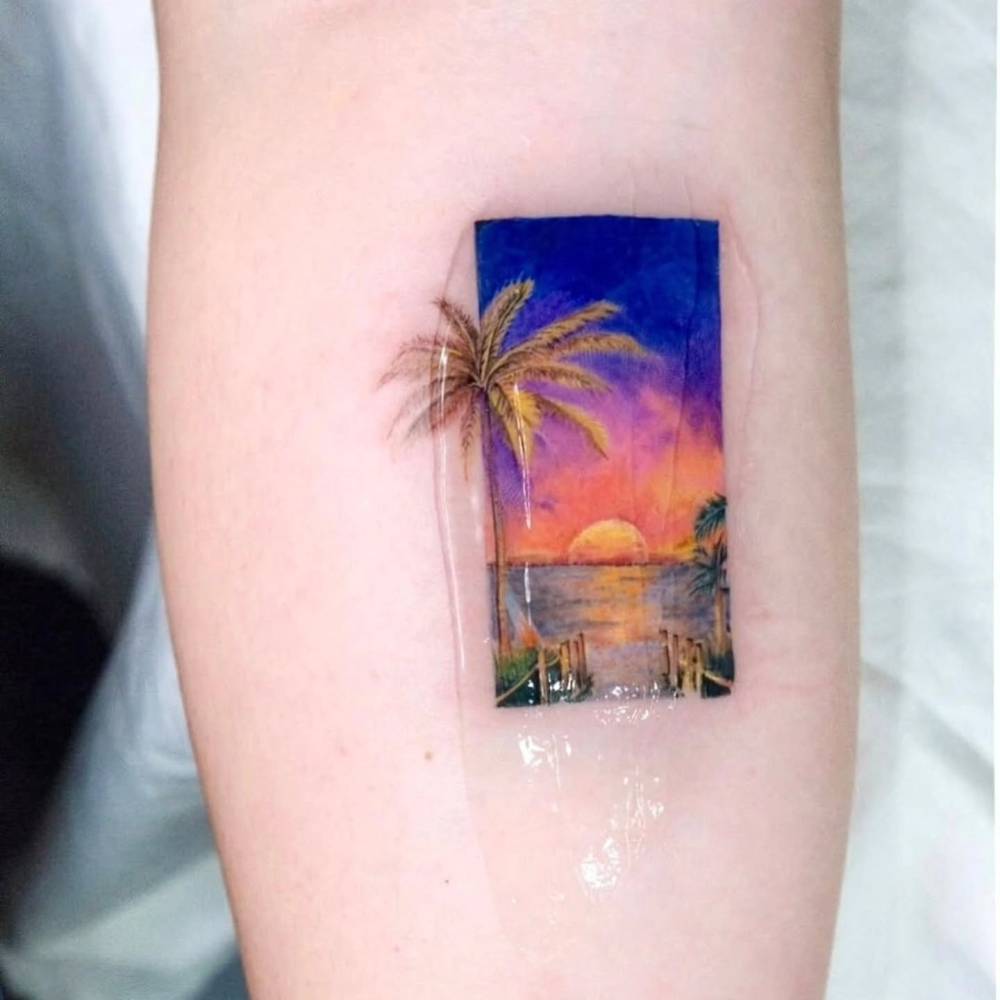 Sunset landscape tattoo in watercolor style located on the calf.