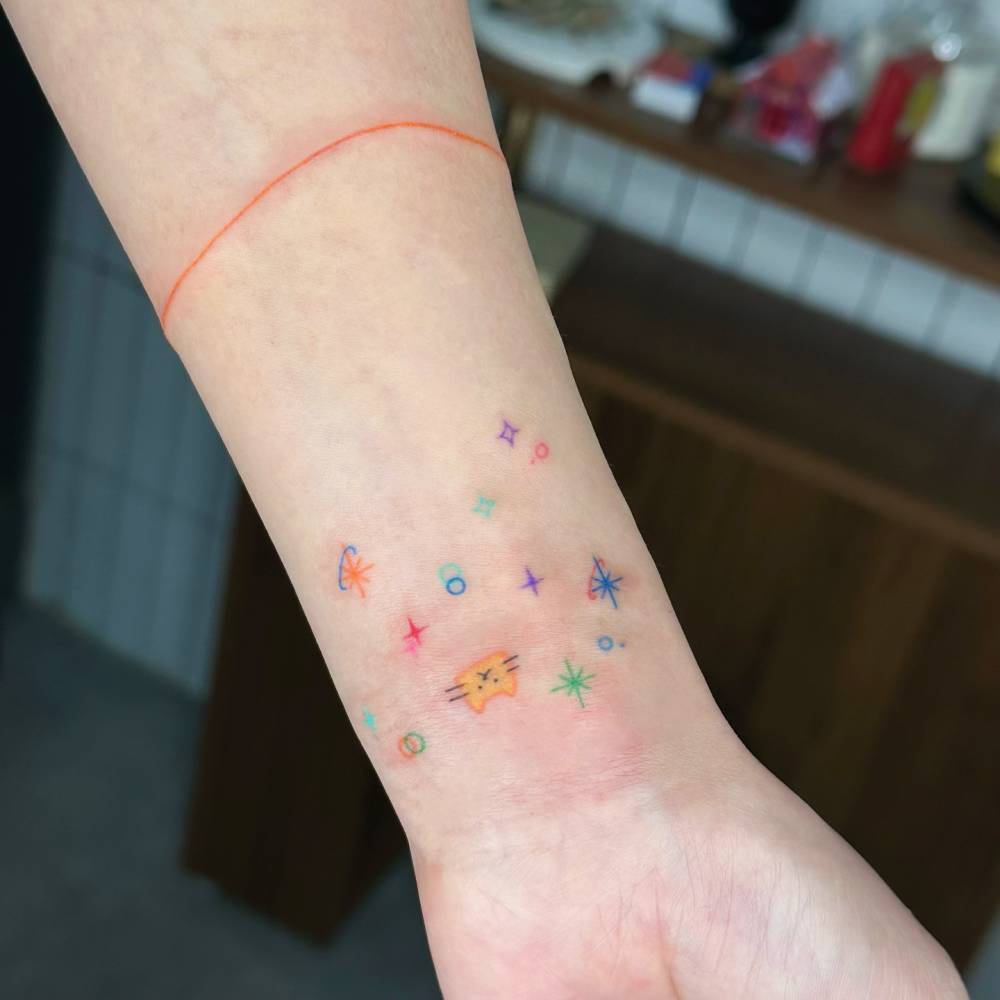 Minimalistic cat and universe tattoo located on the wrist.