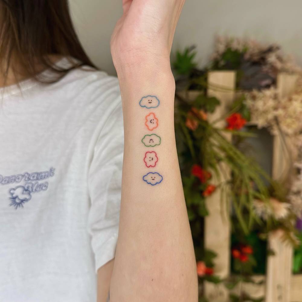 Hand poked clouds tattoo located on the wrist.