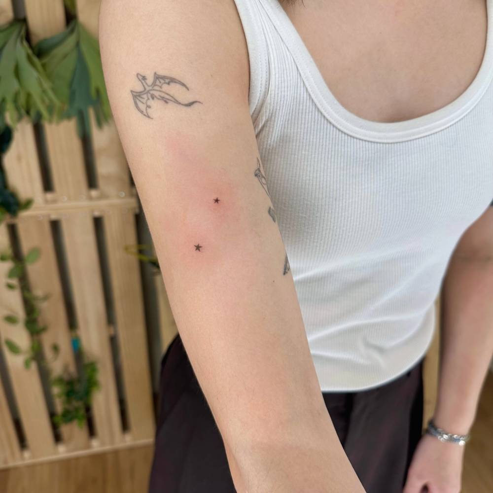 Star couple tattoo in minimalistic style located on the upper arm.