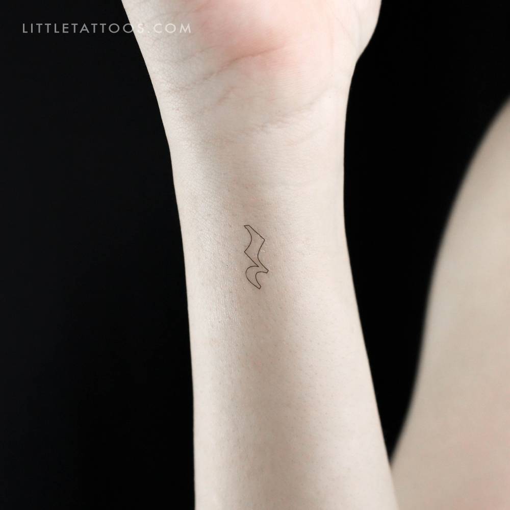 Tiny minimalistic crotchet rest temporary tattoo located on the wrist.