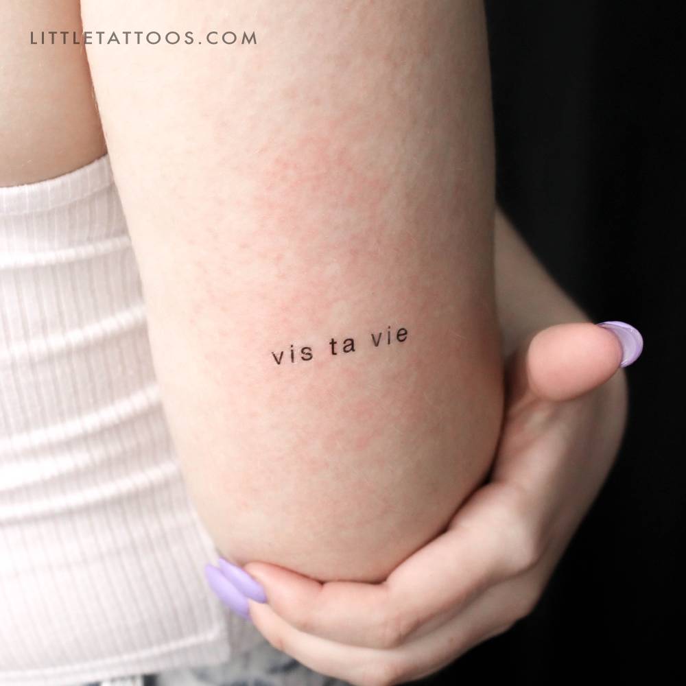 "Vis ta vie" temporary lettering tattoo located on the wrist.