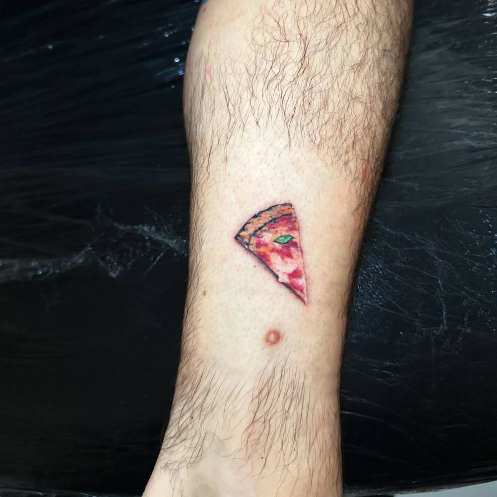 Micro-realistic style pizza margherita tattooed on the shin.