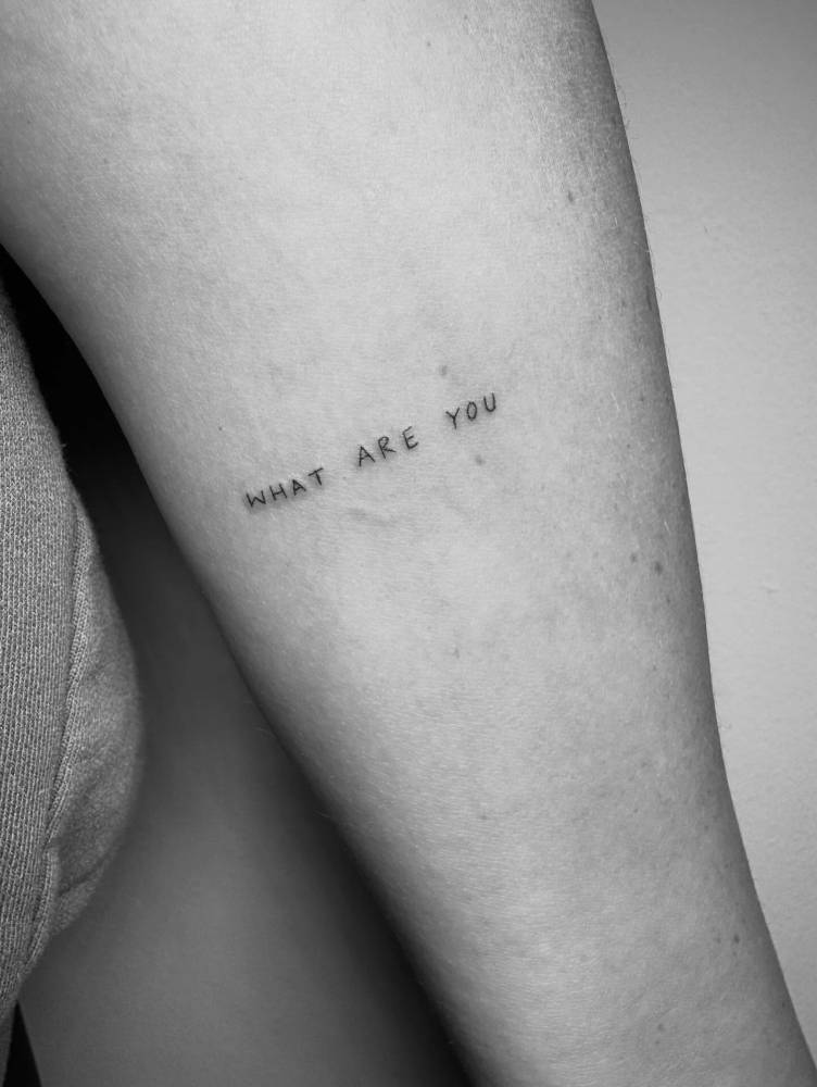 "What are you" lettering tattoo handwritten on the inner forearm.