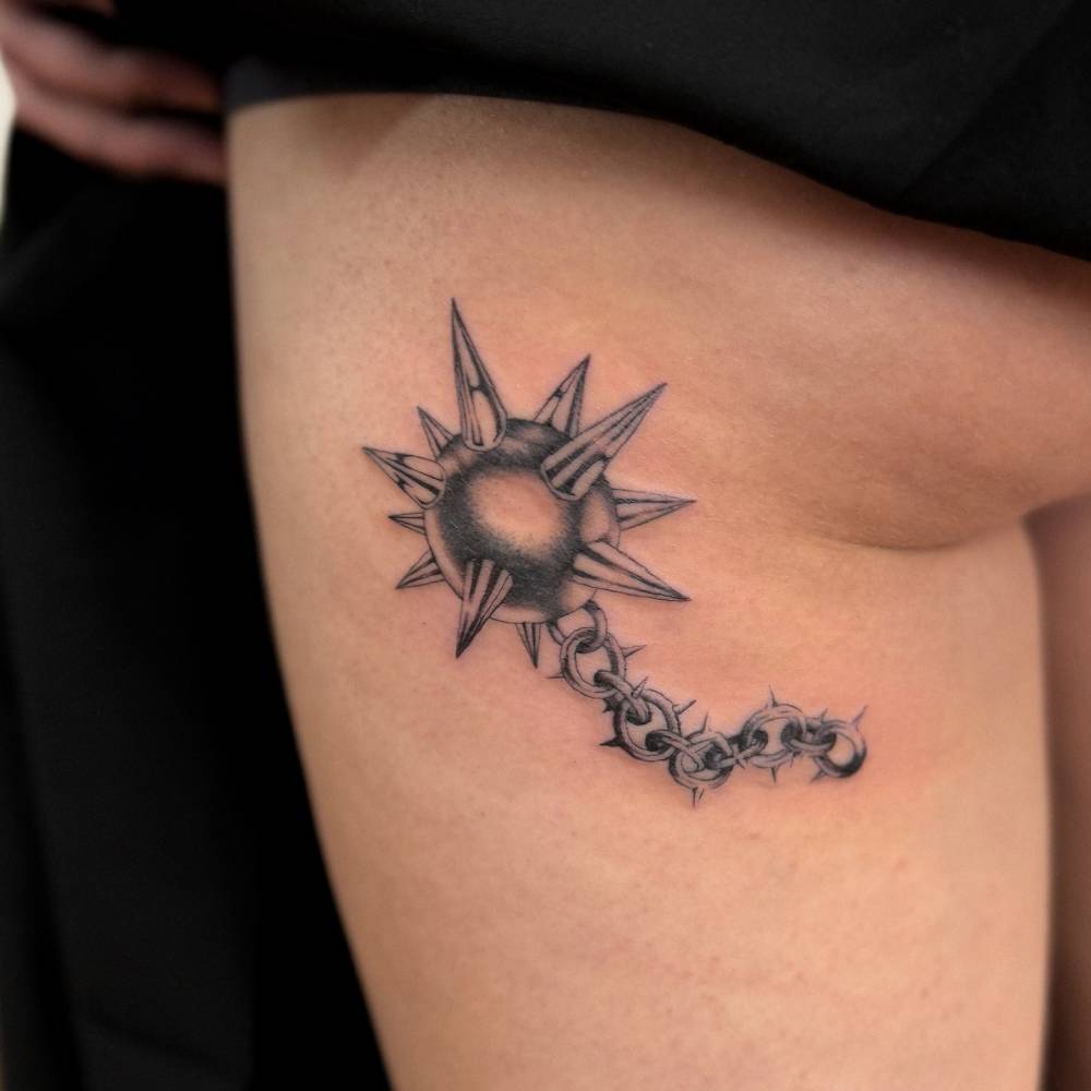Illustrative style flail tattoo located on the thigh.