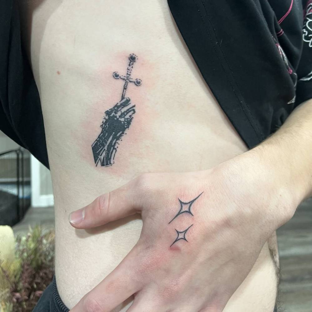 Hands holding a sword tattooed on the rib.