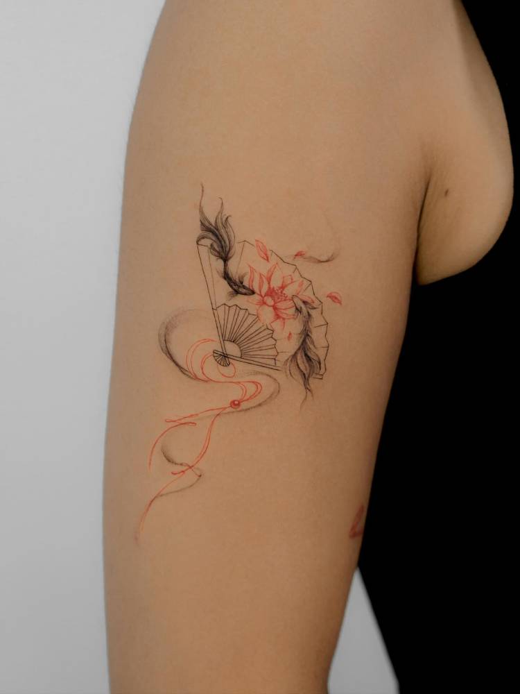 Hand fan and koi fish tattoo located on the upper arm.