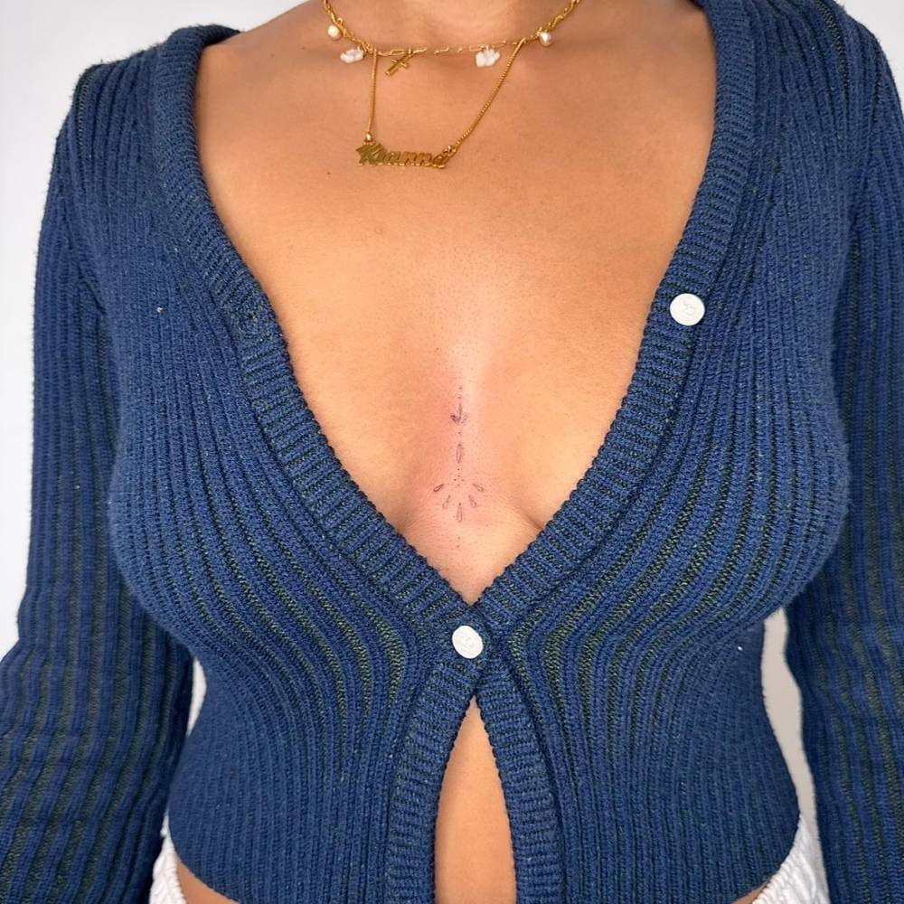 Fine line style ornamental tattoo located on the sternum.