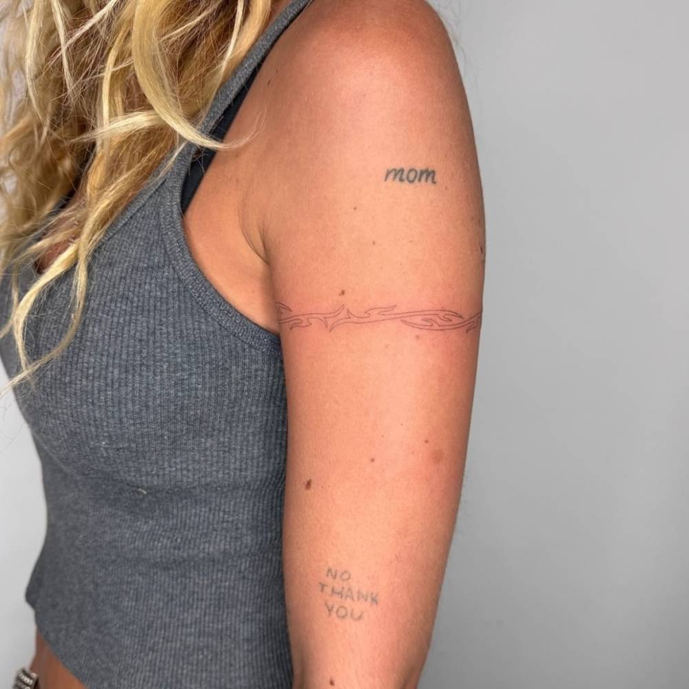 Fine line style tribal bracelet tattooed on the upper arm.