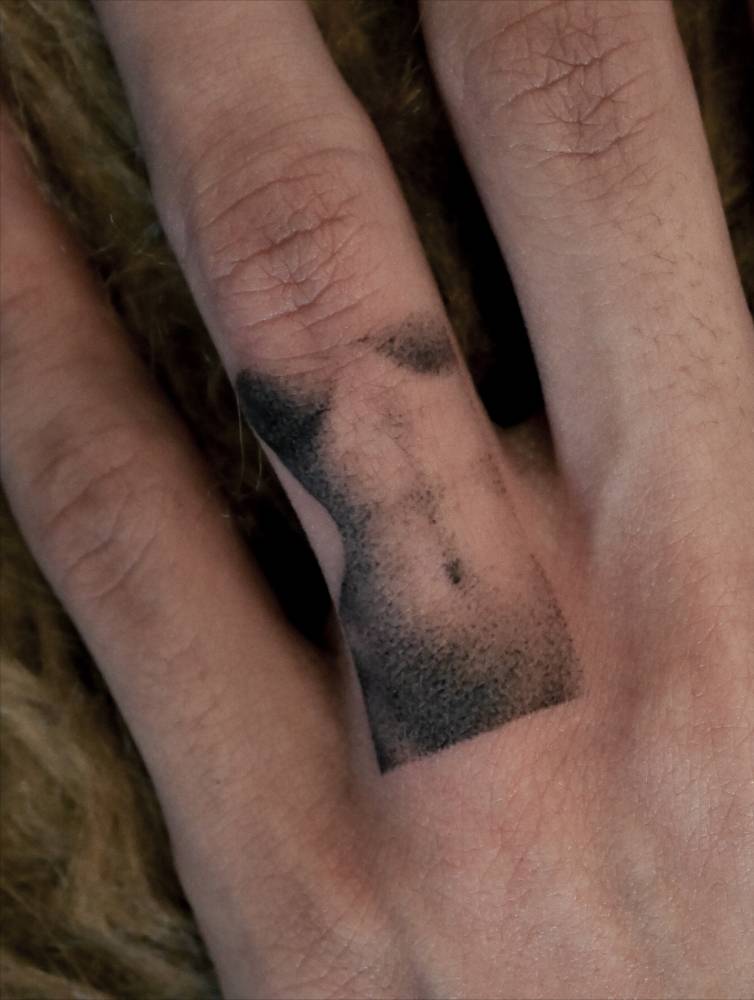 Dotwork style nude woman tattoo located on the finger.