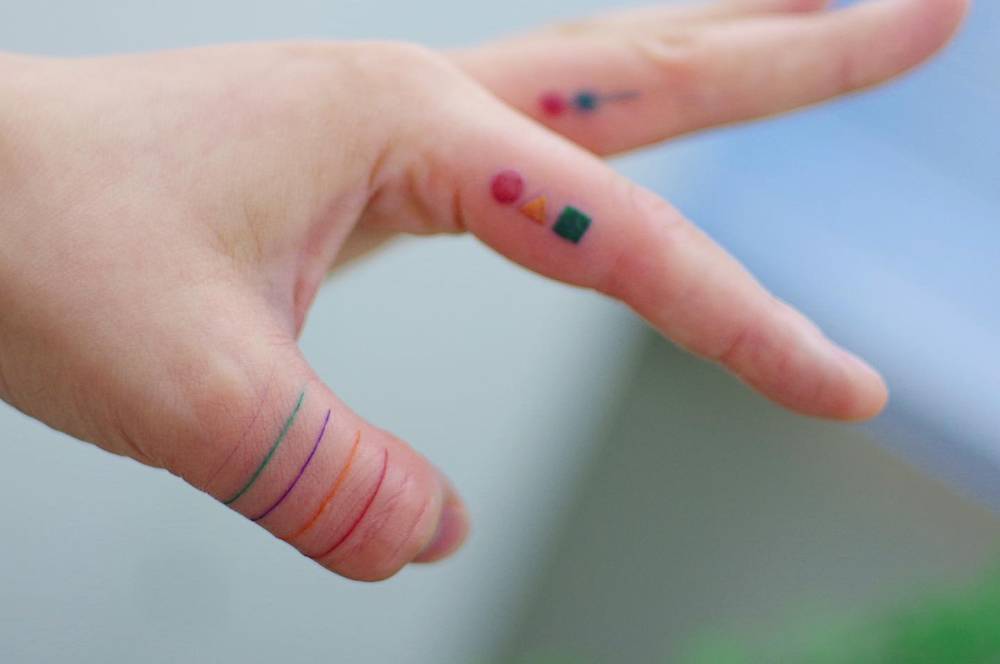 Colorful lines tattooed on the thumb.