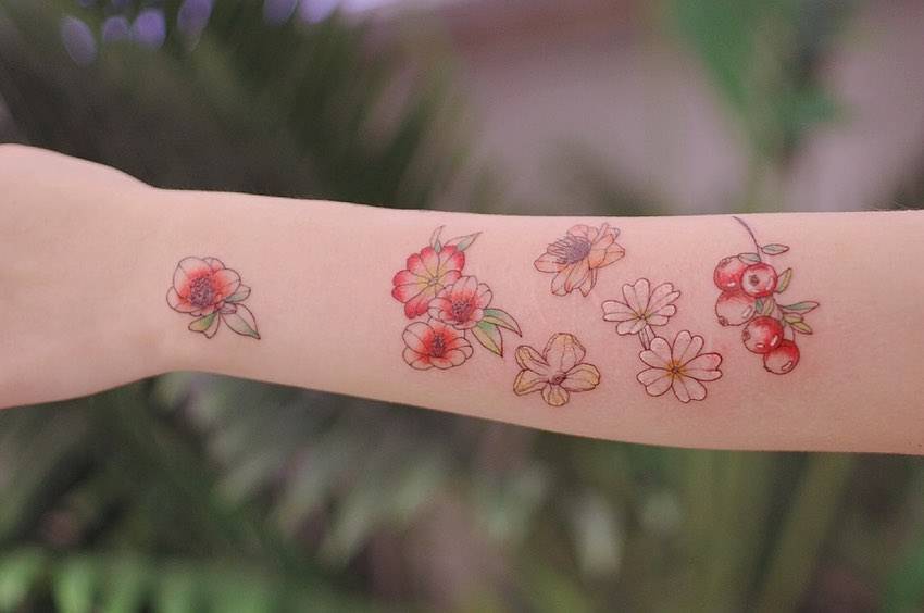 Floral collection in illustrative style tattooed on the forearm.