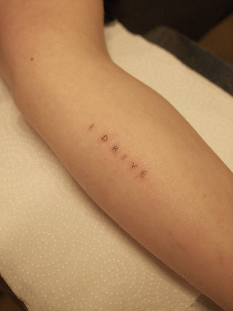 "I drive" lettering tattoo located on the forearm.