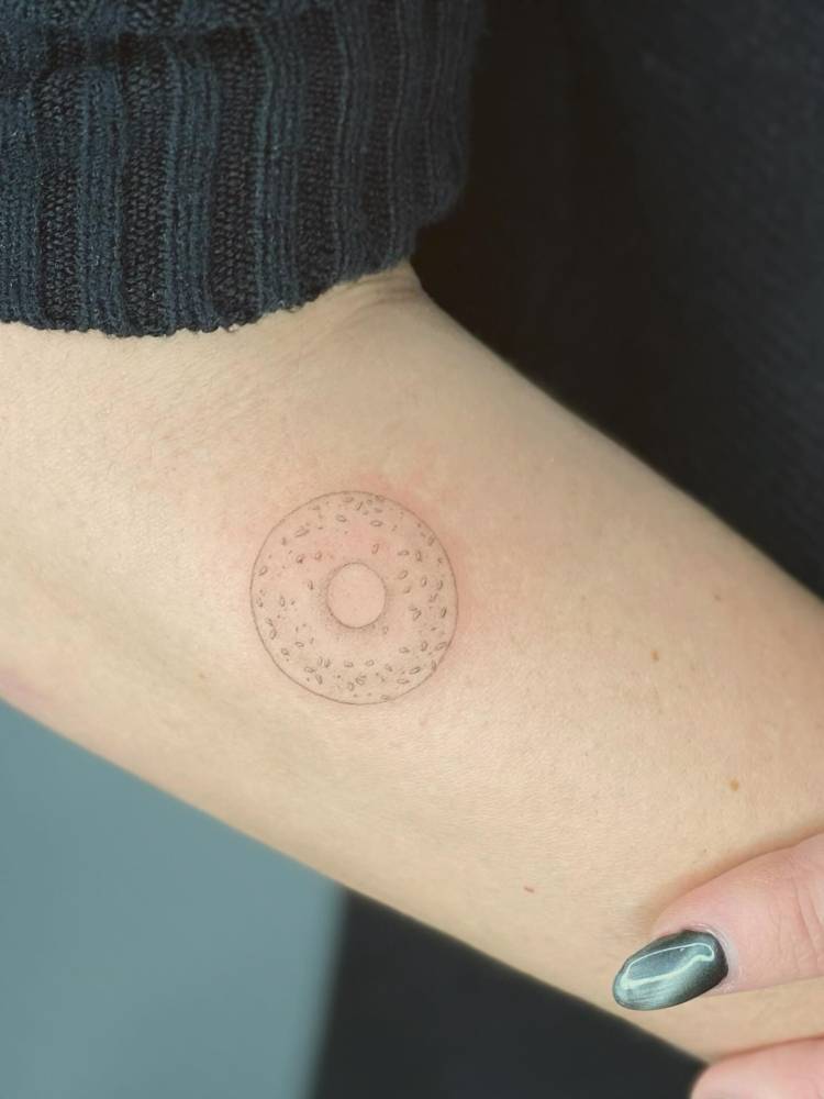 Donut tattoo in fine line style located on the forearm.