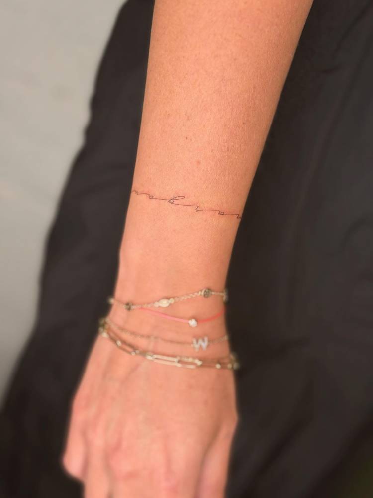 Handwritten font lettering wristband tattoo.