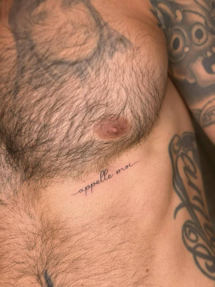 "Appelle moi" lettering tattoo located on the rib.