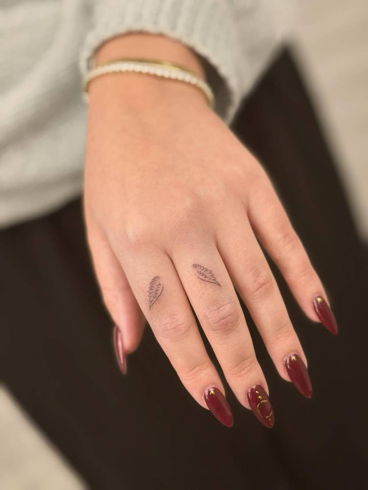 Minimalistic style wings tattoo located on the fingers.