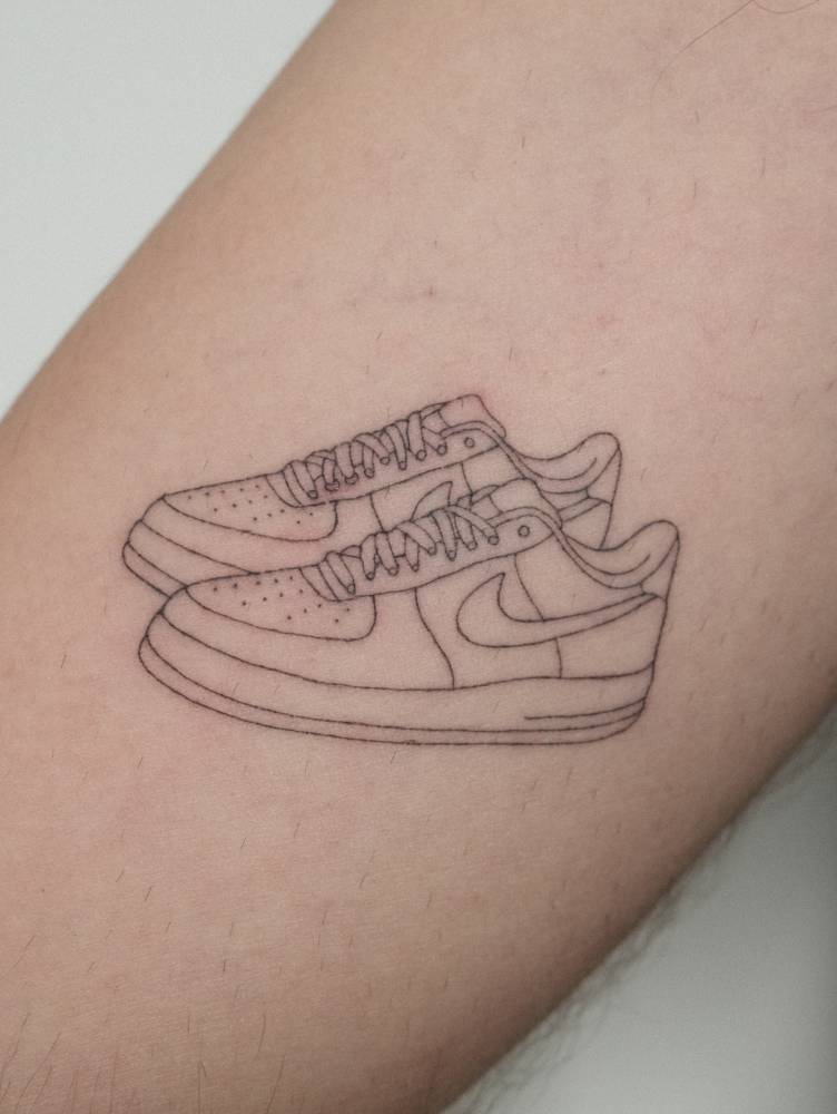 Nike Air Force 1 tattoo in fine line style located on the inner arm.
