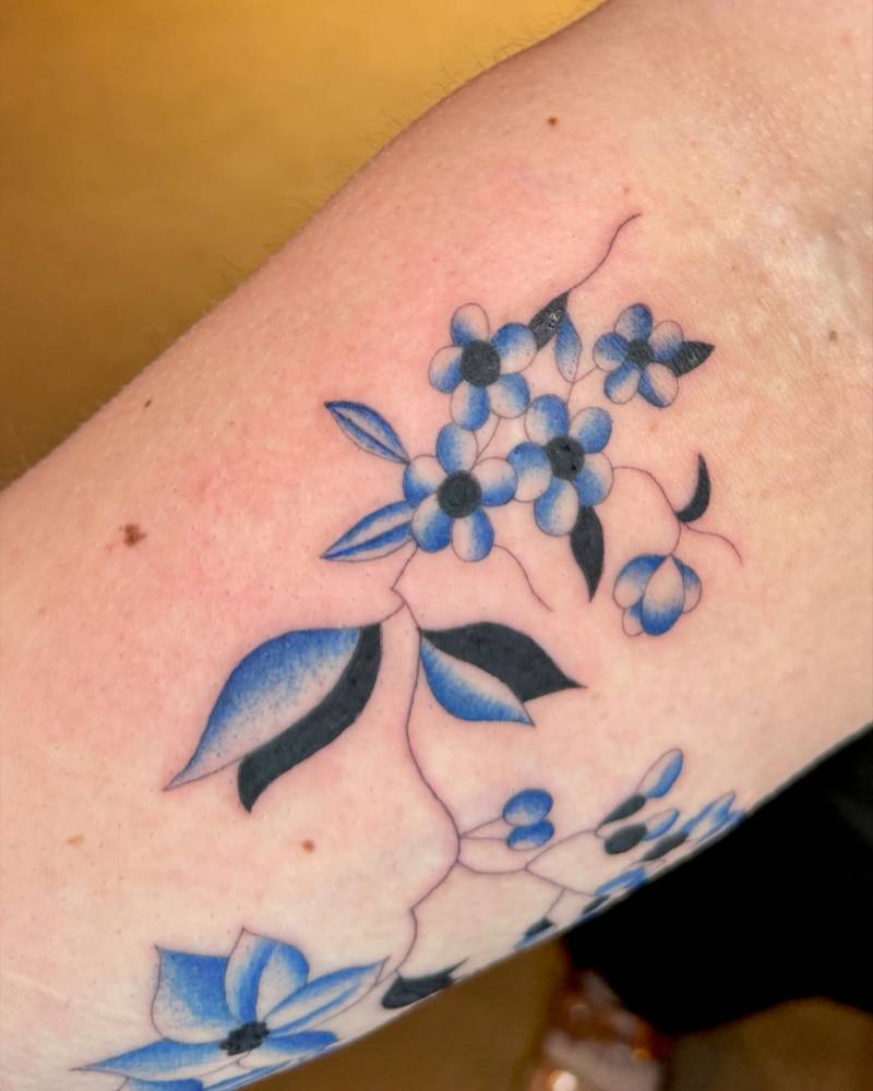 Forget-me-not tattoo in illustrative style located on the inner forearm.
