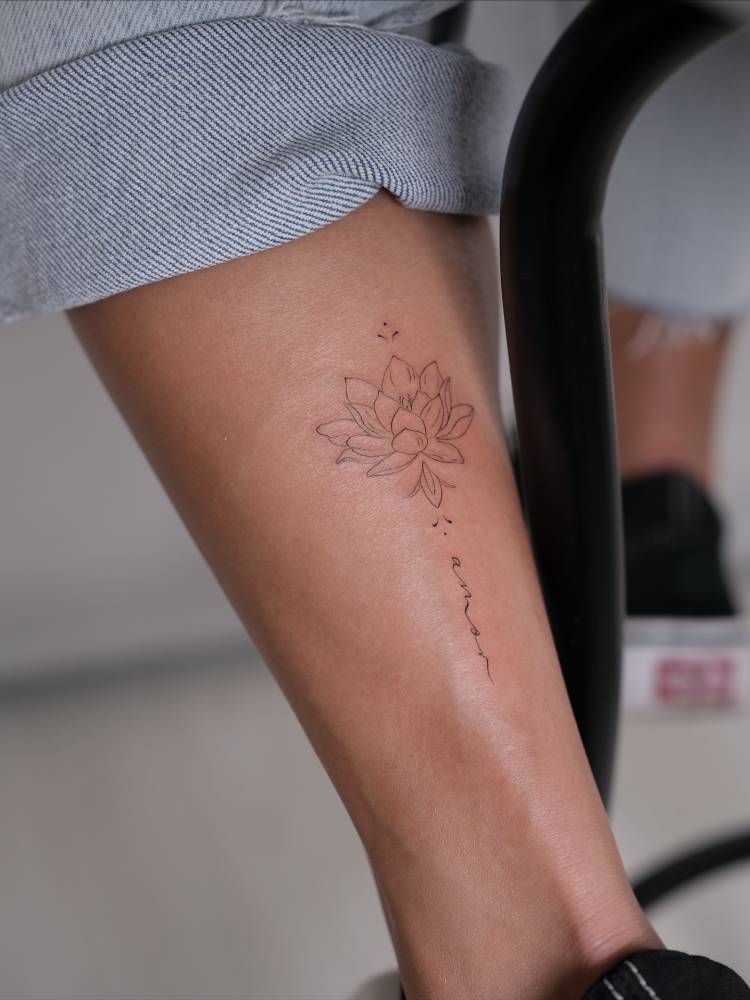 Fine line style lotus flower and word "amor" tattoo located on the achilles.