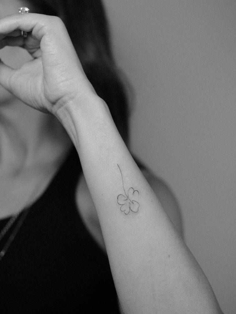 Continuous line four leaf clover tattoo located on the wrist.