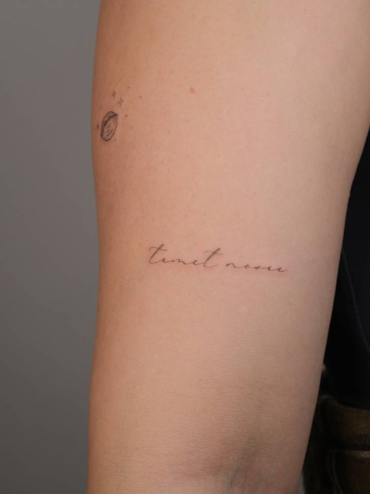 "Temet nosce" lettering tattoo located on the upper arm.