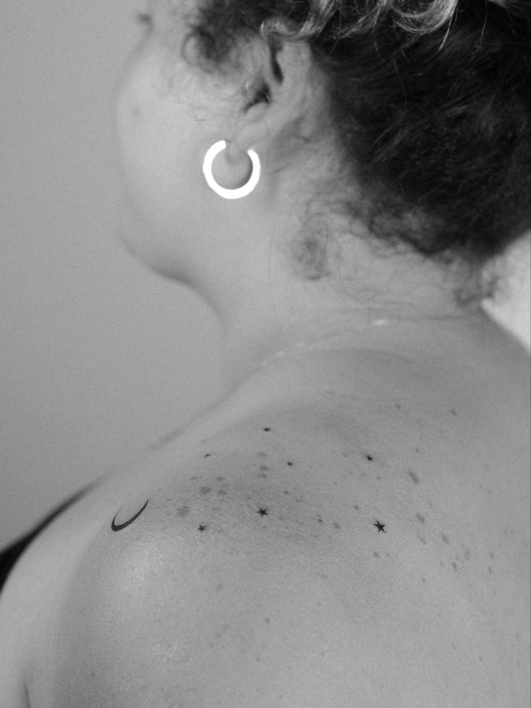 Moon and stars tattoo in minimalistic style located on the shoulder.
