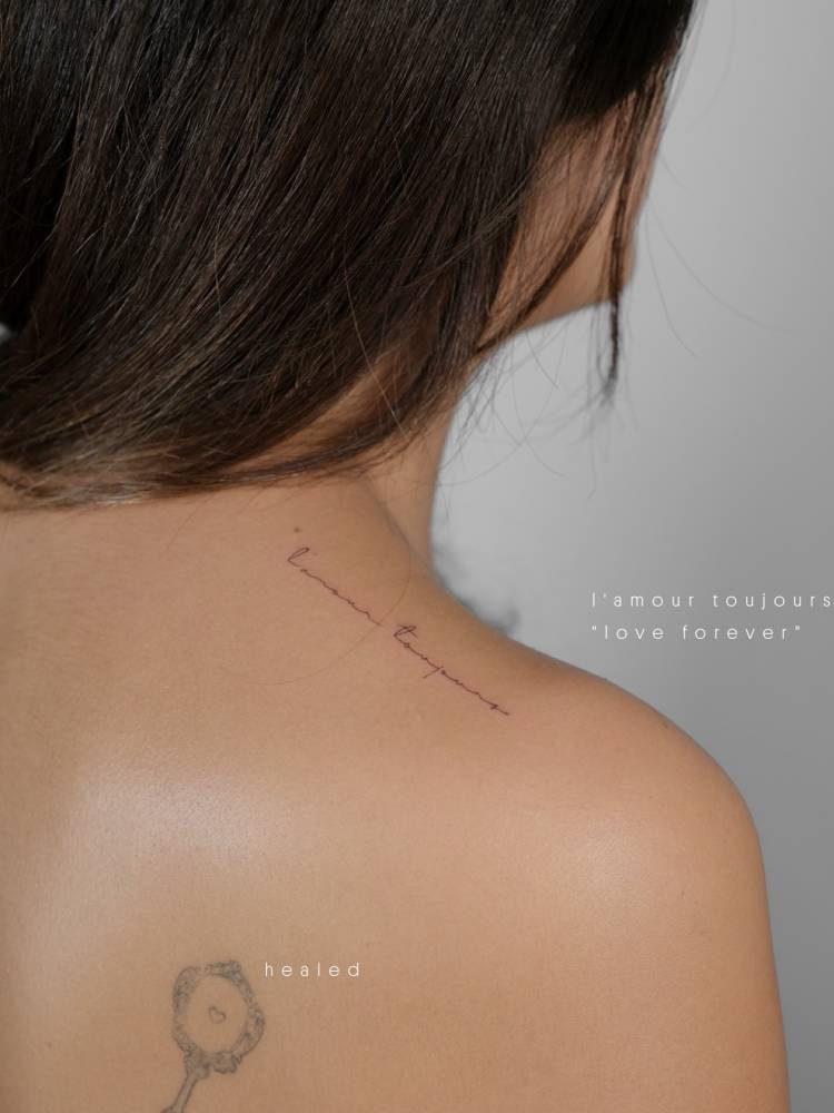 "L'amour toujours" lettering tattoo handwritten on the top of shoulder.