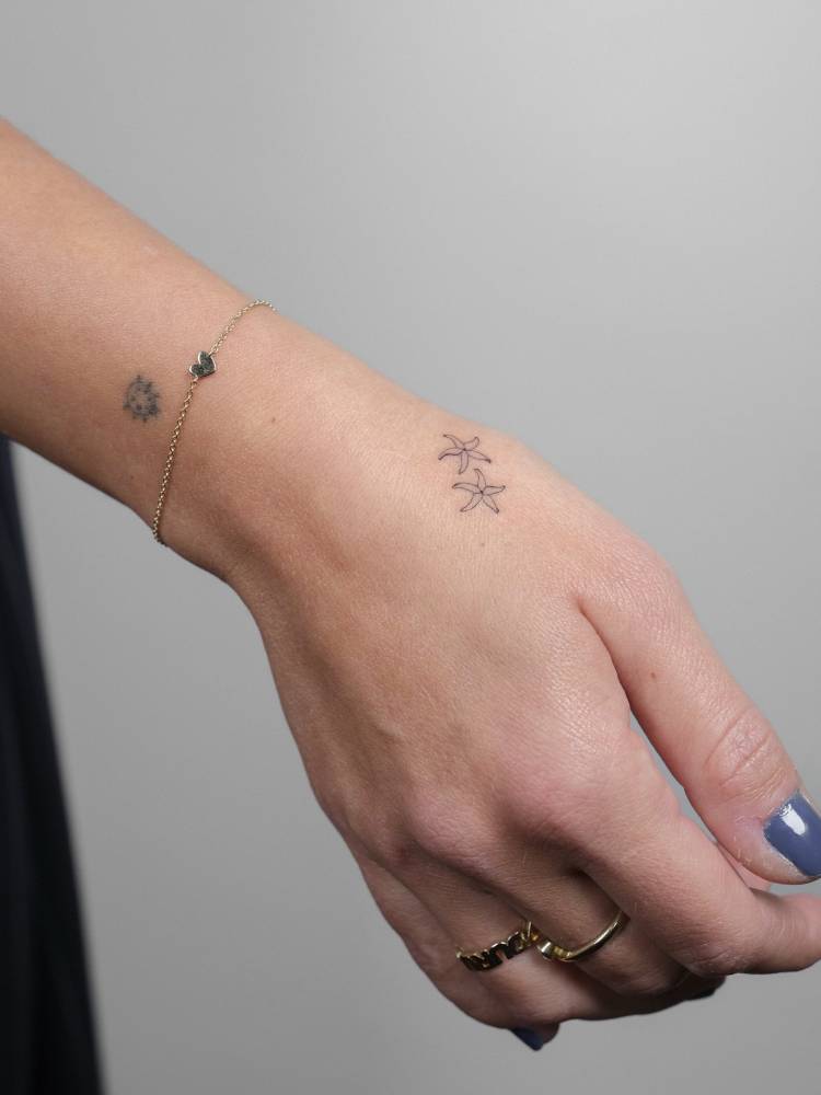 Star jasmine tattoo in minimalistic style located on the hand.