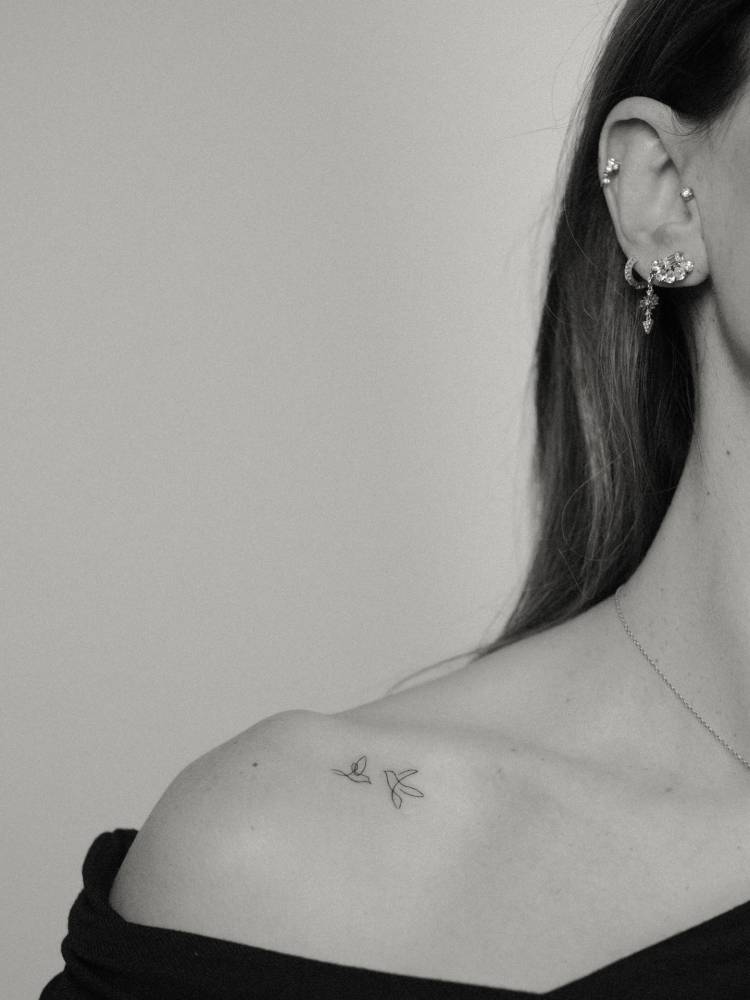 Tiny flying birds tattoo located on the shoulder, minimalistic style.