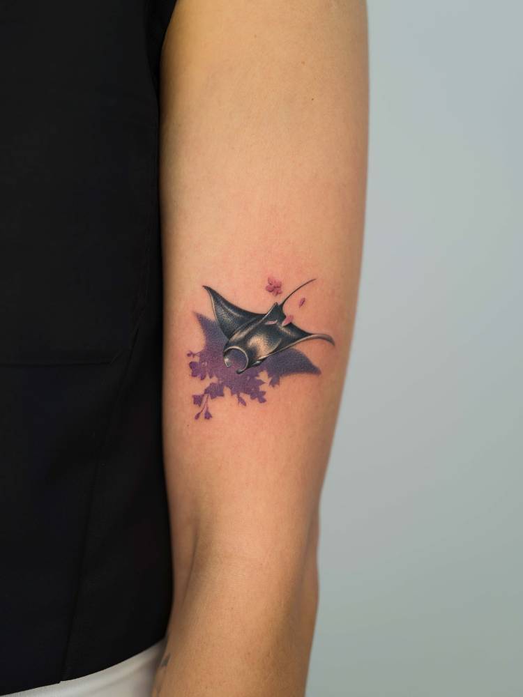 Manta ray and flowers tattooed on the upper arm.
