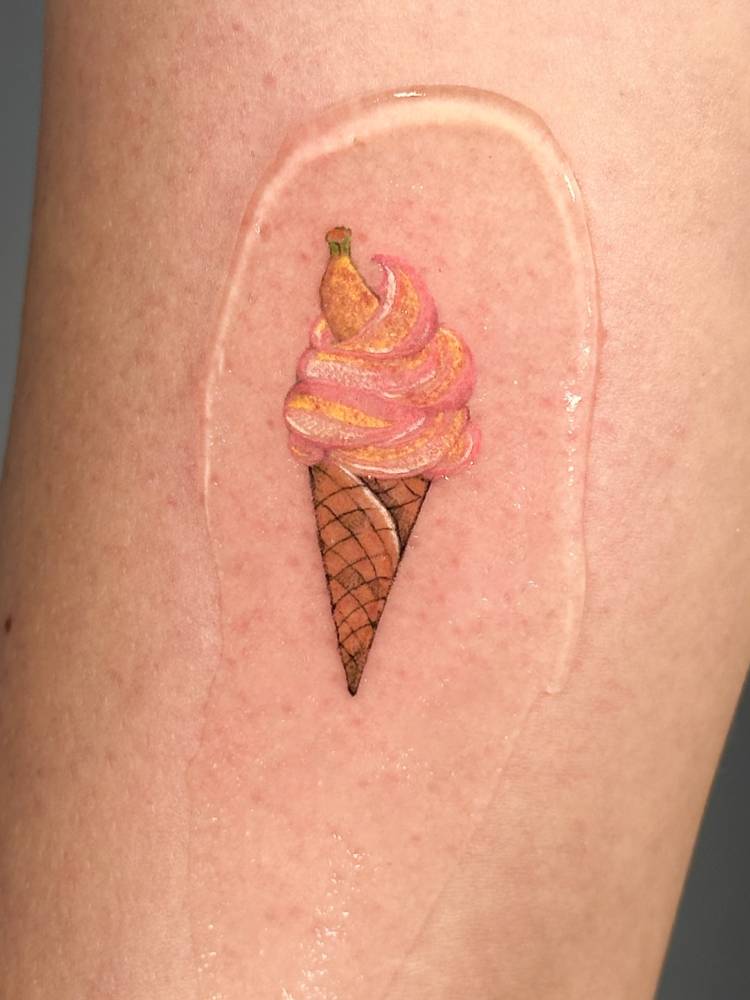 Ice cream cone tattoo in watercolor style done on the inner forearm.