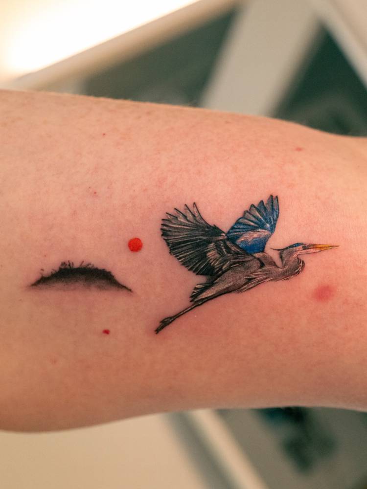 Heron tattoo in illustrative style located on the wrist.