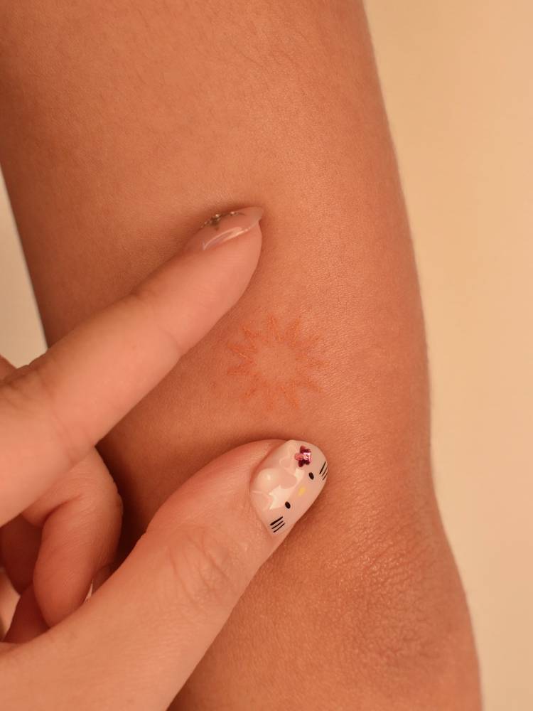 Minimalistic style sun tattoo located on the tricep.