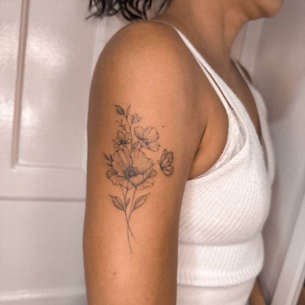 Flower bouquet and butterfly tattoo located on the upper arm.