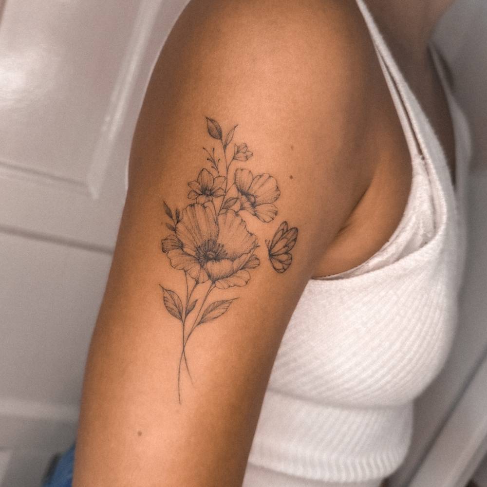 Flower bouquet and butterfly tattoo located on the upper arm.