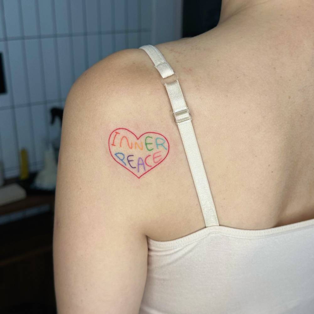Hand poked "inner peace" heart and banner tattoo located on the shoulder blade.