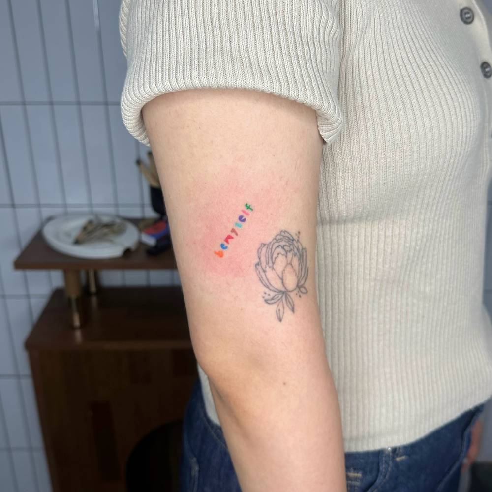 "Be myself" colorful lettering tattoo hand poked on the upper arm.