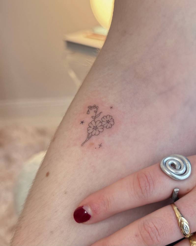 Fine line style little flowers tattooed on the inner forearm.