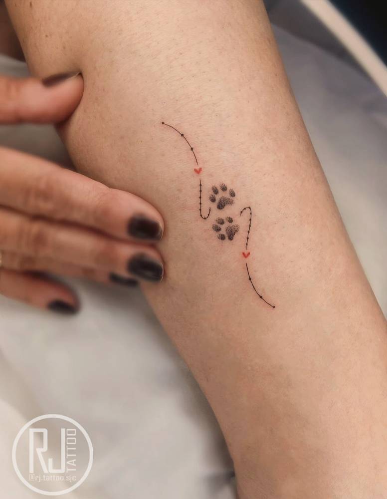 Dog paw print tattoo in illustrative style located on the shin.