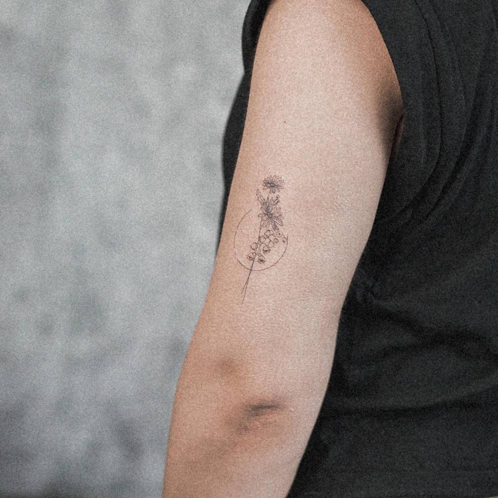 Fine line flower bouquet tattoo located on the upper arm.