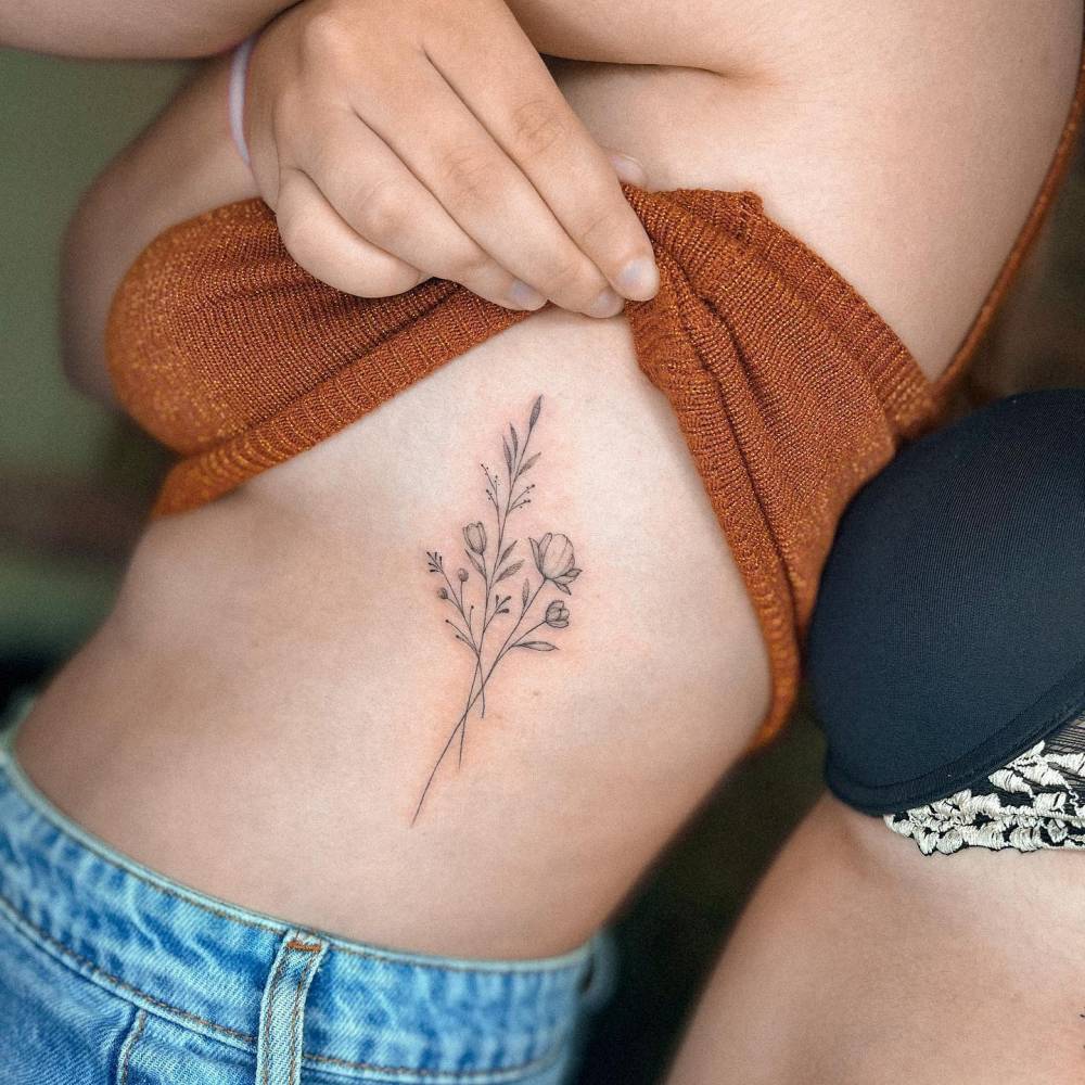 Fine line flower bouquet tattoo located on the rib.