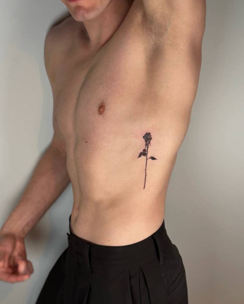 Black rose tattoo located on the rib.