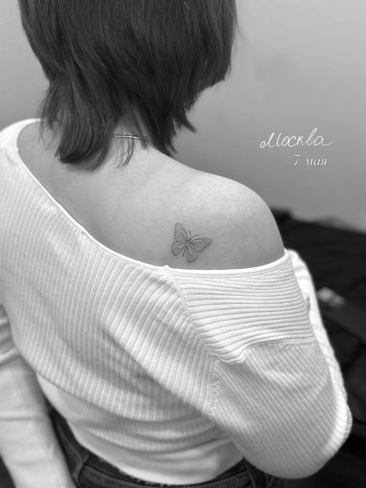 Butterfly tattoo located on the shoulder blade, done in fine line style.