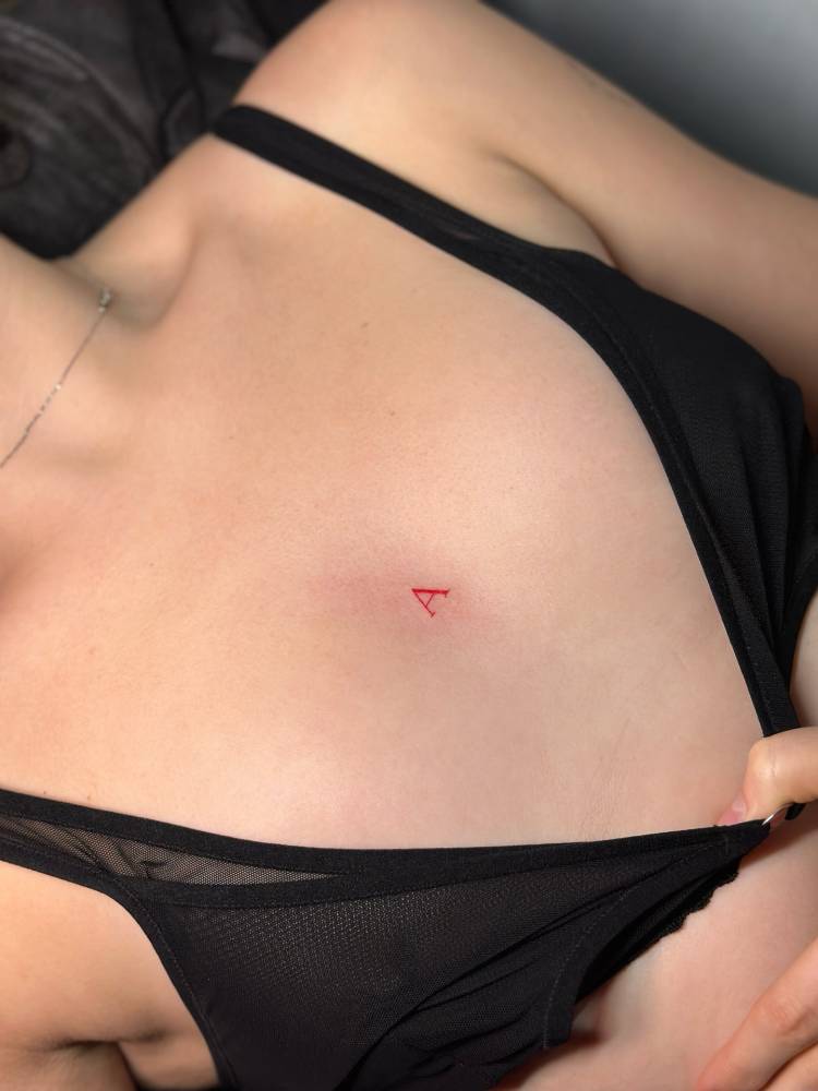 Letter "A" tattoo in red ink placed on the sternum.